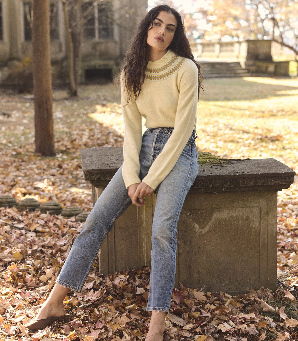 Woman is wearing a light yellow fair isle sweater with jeans.