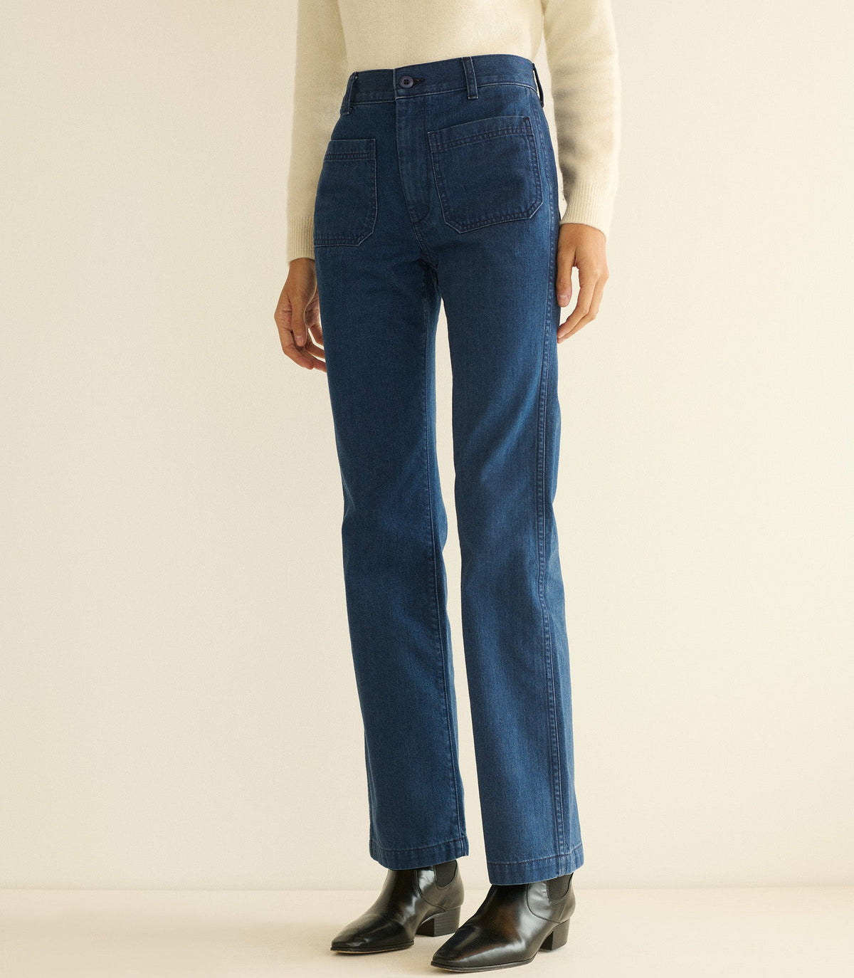 Blue jeans worn by a person on a beige background
