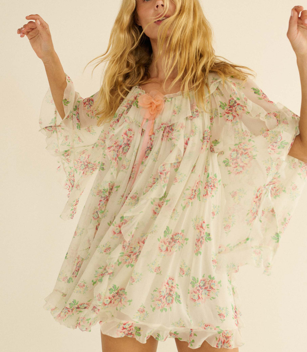 Woman wearing a white floral dress against a plain background
